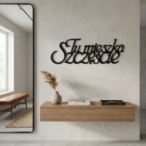 Czarny metalowy napis Tu mieszka szczęście zamontowany na jasnej ścianie w ciepłym, przytulnie urządzonym pokoju z domowymi dodatkami.