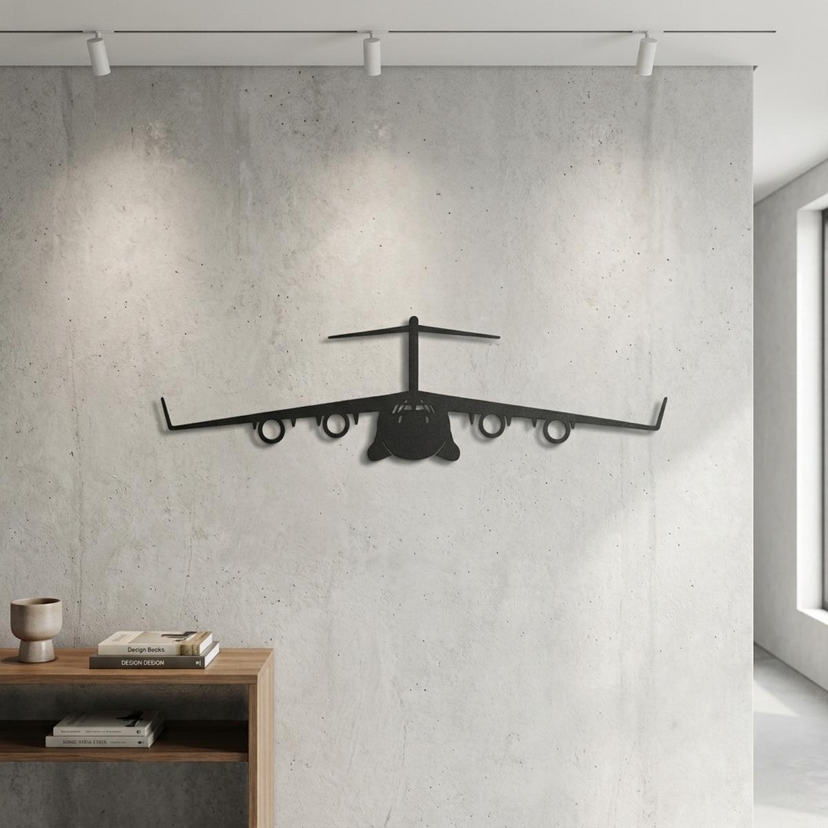 Czarny metalowy samolot wojskowy Boeing C-17 Globemaster zawieszony na betonowej ścianie z reflektorami pod sufitem