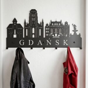 Zbliżenie na solidny wieszak metalowy z napisem Gdańsk, Fontanną Neptuna i Bazyliką Mariacką. Na zagiętych hakach wiszą skórzana kurtka i płaszcz.