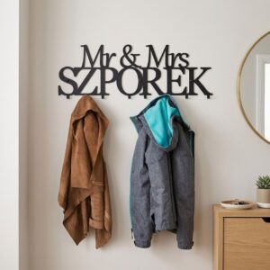 Czarny, personalizowany wieszak metalowy do przedpokoju z wyciętym napisem Mr & Mrs SZPOREK. Na hakach wiszą kurtki.