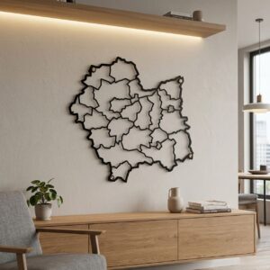 Czarna ażurowa mapa województwa małopolskiego z podziałem na powiaty zawieszona nad drewnianą szafką w jasnym salonie.