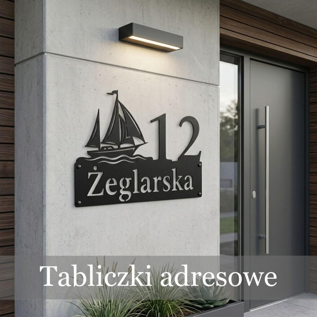 Nowoczesna tabliczka adresowa z numerem 12 i ulicą Żeglarską oraz motywem jachtu, zamontowana na betonowym filarze wejściowym pod lampą.