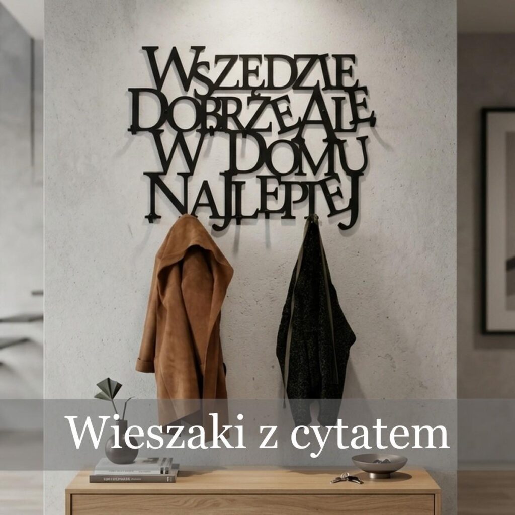Czarny metalowy wieszak na ubrania z napisem Wszędzie dobrze ale w domu najlepiej, zamontowany w przedpokoju nad szafką.