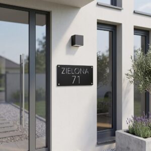 Nowoczesna czarna tabliczka adresowa Model Loft z numerem 71 zamontowana na białej elewacji domu przy drzwiach wejściowych